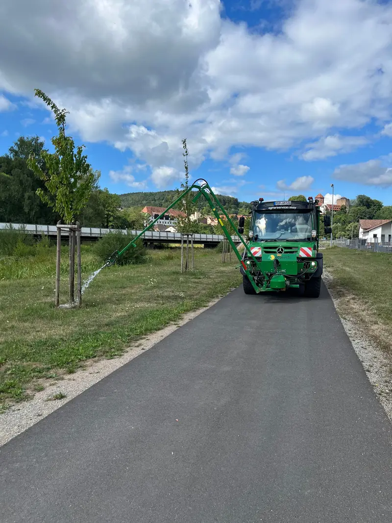 Unimog mit Fassaufbau beim Gießen junger Straßenbäume