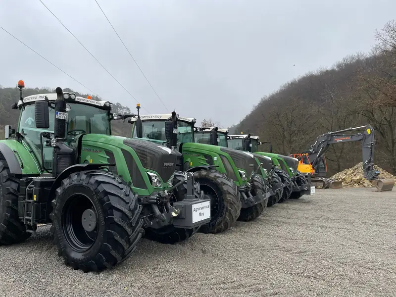 Fendt Schlepper von Agrarservice May in einer Reihe auf dem Betriebshof, dahinter ein Bagger